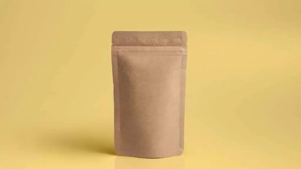Brown kraft paper stand-up pouch standing upright on a yellow background.